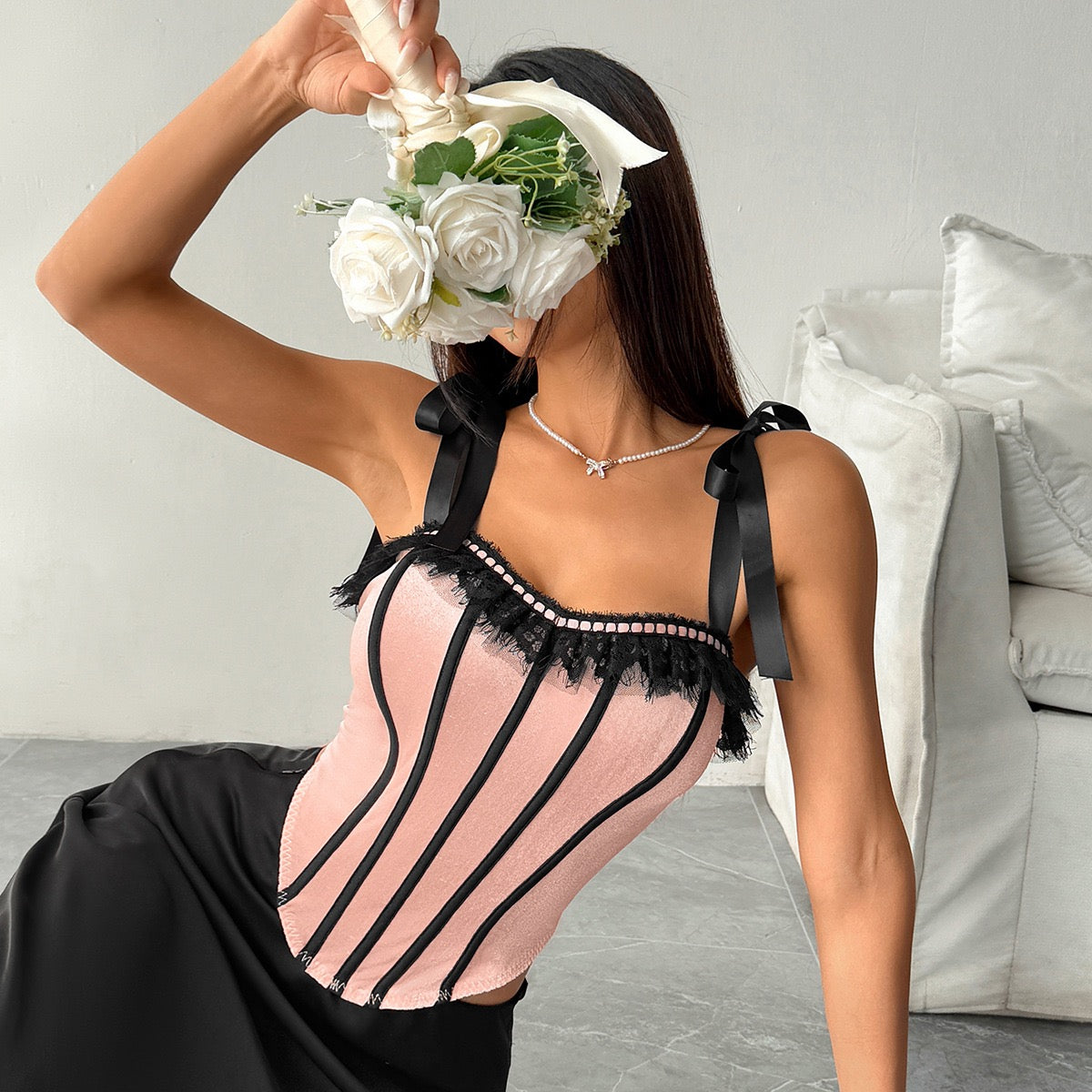 Model styling pink velvet corset top with black satin skirt in studio setting